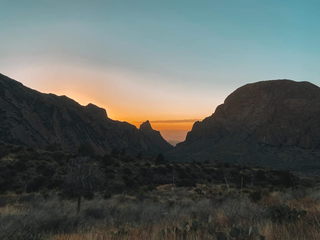 an orange sunset between two peaks called the "Windows" in Big Bend National Park