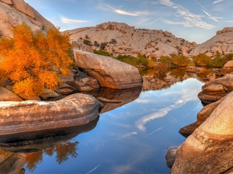 A small pond at sunset surrounded by smooth rocky boulders. 